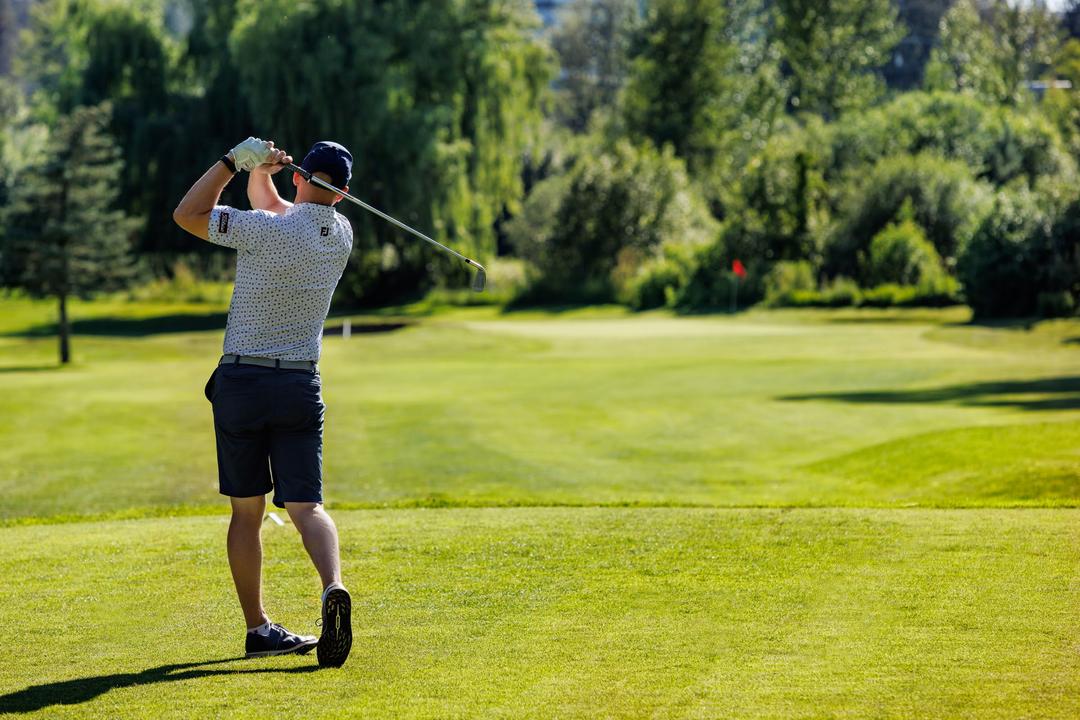 Golfer swinging down a fairway